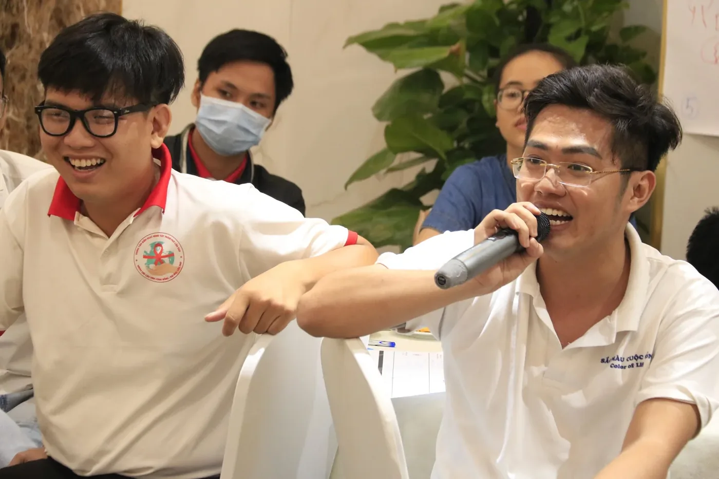 Workshop participant speaking into a microphone while others laugh